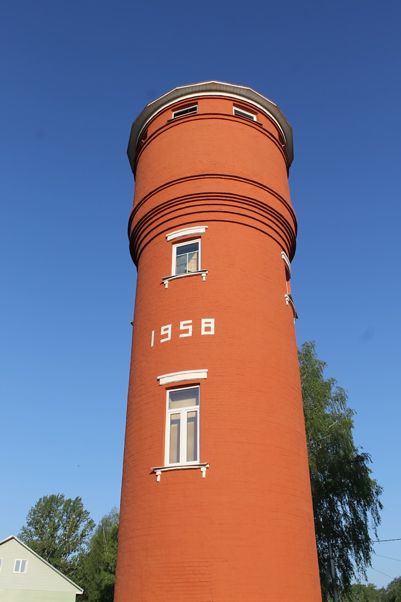 a tall red tower with a clock on it's side